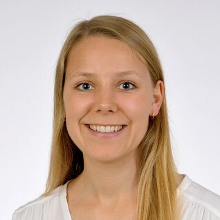 Portrait einer jungen Frau mit langen, blonden Haaren und hellem Hintergrund.